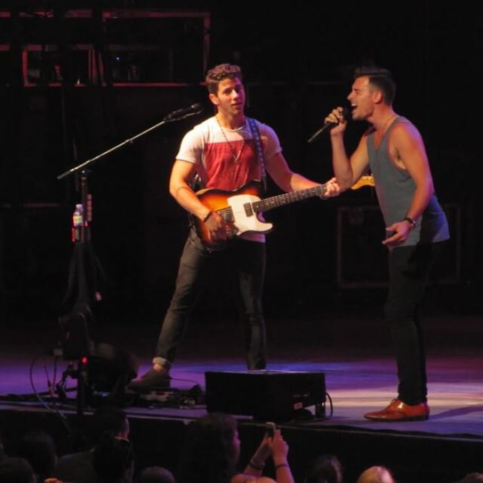 Jordan Baird (R) performs with Nick Jonas.