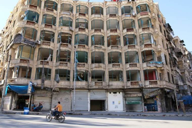 A man rides a motorcycle past a damaged building in the rebel-held al-Shaar neighbourhood of Aleppo, Syria, September 17, 2016.