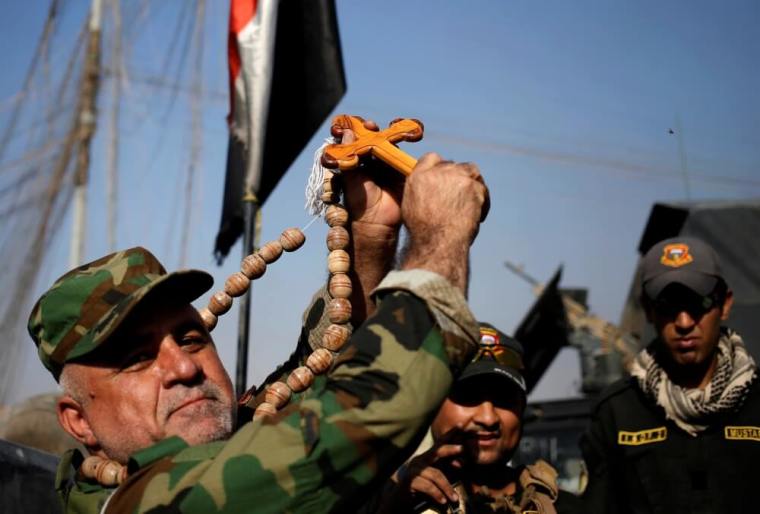 A Christian militiaman holds up a cross in front of Iraqi special forces soldiers in Bartella, east of Mosul, Iraq October 22, 2016.