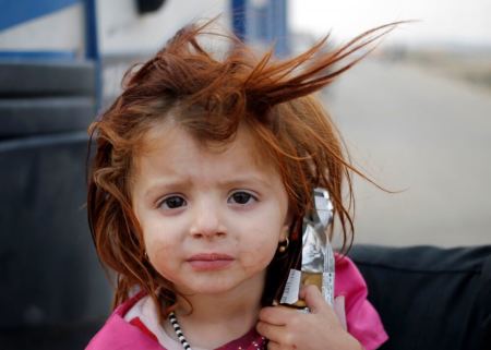 An internally displaced girl is carried by her father on a road near Hassan Sham, east of Mosul, Oct. 25, 2016.