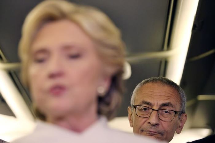 John Podesta, chairman of U.S. Democrat Hillary Clinton's presidential campaign, listens as she talks to the media inside of her campaign plane after the third and final 2016 presidential campaign debate in North Las Vegas, Nevada, U.S., October 19, 2016.