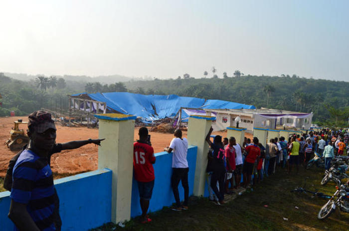 People are seen behind the fence of the collapsed Reigners Bible Church in Uyo, Nigeria Dec. 11, 2016.