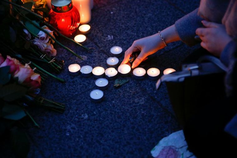 A woman places lit candles at the Christmas market in Berlin, Germany, December 20, 2016, where a truck ploughed into the crowd on Monday.