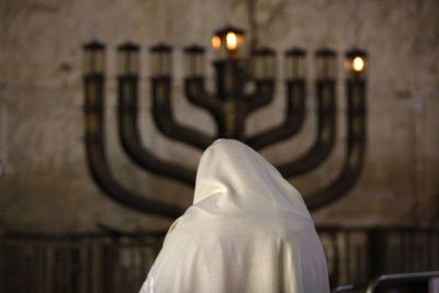 A Jewish man prays in front Menorah candles on the first night of the Jewish festival of Hanukkah at the Western Wall in Jerusalem's Old City December 21, 2008. Hanukkah, which means 'dedication', and is also referred to as 'The Festival of Lights', comme