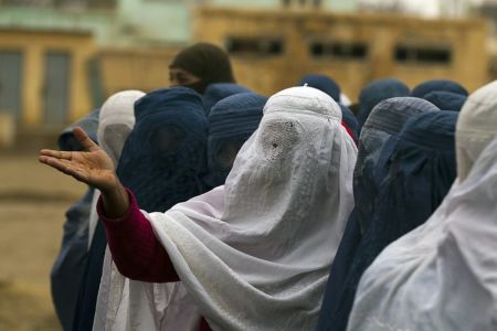 An Afghan woman reacts as she waits in a line to vote at a polling station in Mazar-i-Sharif April 5, 2014. Voting was peaceful during the first few hours of Afghanistan's presidential election on Saturday, with only isolated attacks on polling stations as the country embarked on the first democratic transfer of power since the fall of a Taliban regime in 2001.