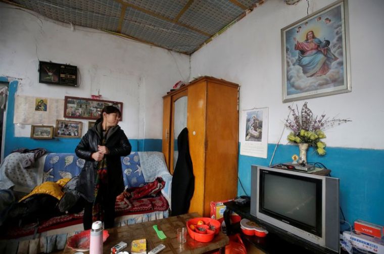 A villager checks her coat before she leaves for a Christmas mass at a Catholic church on the outskirts of Taiyuan, North China's Shanxi province, December 25, 2016.