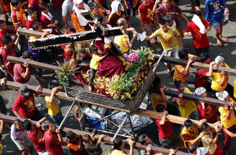 A girl hugs a replica of the black statue of Jesus Christ during the annual Black Nazarene Catholic religious procession in Manila, Philippines, January 9, 2017.