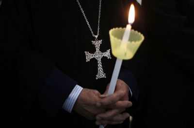 A Coptic Christian holds a lit candle in remembrance of the Egyptians beheaded in Libya, in the West Bank city of Ramallah February 17, 2015. Egyptian President Abdel Fattah Al-Sisi called for a United Nations resolution mandating an international coalition to intervene in Libya after Egypt's air force bombed Islamic State targets there. Egypt directly intervened for the first time in the conflict in neighbouring Libya on Monday after an Islamic State group in the country released a video showing the beheading of 21 Egyptian Christians.