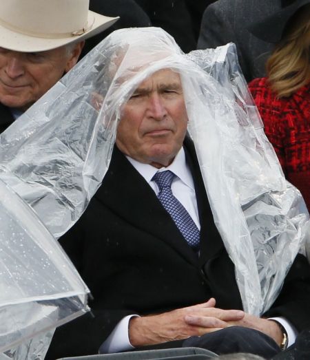 Former President George W. Bush keeps covered under the rain during the inauguration ceremonies swearing in Donald Trump as the 45th president of the United States on the West front of the U.S. Capitol in Washington, U.S., January 20, 2017.