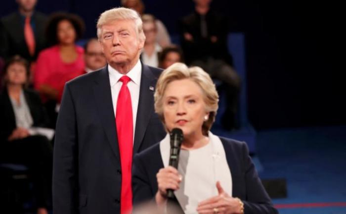 Republican U.S. presidential nominee Donald Trump listens as Democratic nominee Hillary Clinton answers a question from the audience during their presidential town hall debate at Washington University in St. Louis, Missouri, U.S., October 9, 2016.