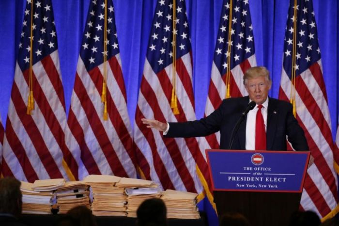 Then President-elect Donald Trump gestures to documents that allegedly transferred 'complete and total control' of his businesses while he speaks at a news conference in the lobby of Trump Tower in NYC on Jan. 11, 2017.