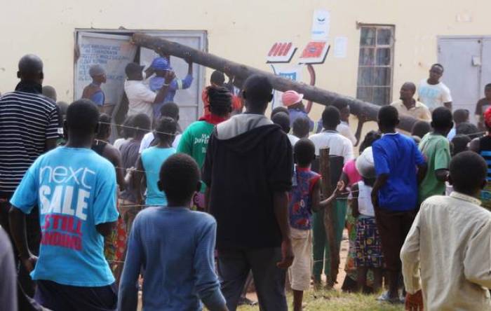 People use a pole to batter a shop doorway during clashes with police in Lusaka April 19, 2016.