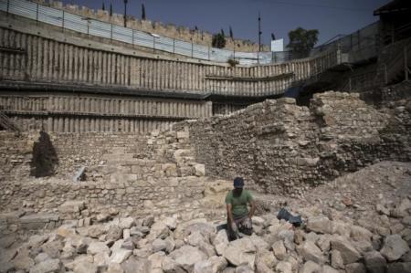 An Israeli antiquity authority worker removes dust at a site that archaeologists say contains the remnants of an ancient Greek fortress, outside the walled Old City of Jerusalem, November 3, 2015.