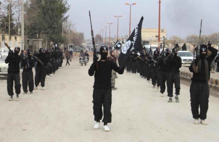 ISIS fighters carry their weapons as they parade along a street in an occupied territory in Syria.