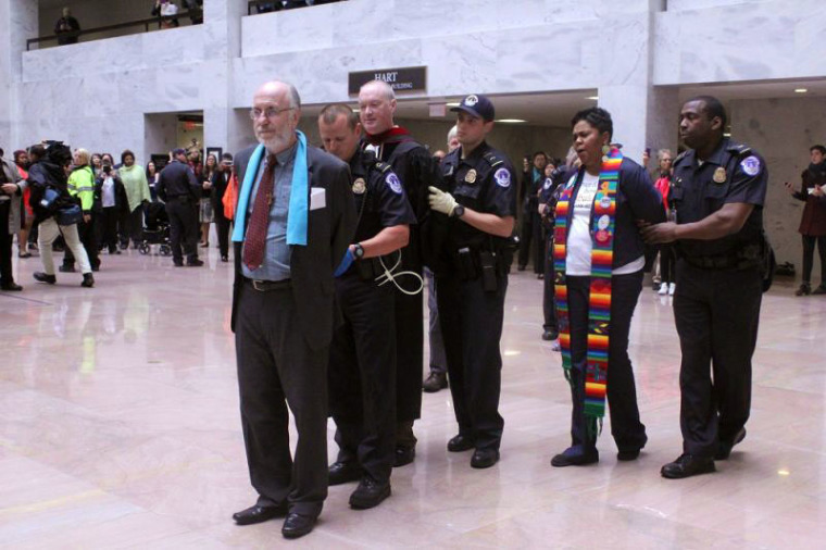 Patrick Carolan (L), Doug Grace (M) and Traci Blackmon (R) are detained by Capitol Police officers for demonstrating against the proposed budget of President Donald Trump at the Hart Senate Office Building in Washington, D.C. on April 24, 2017.