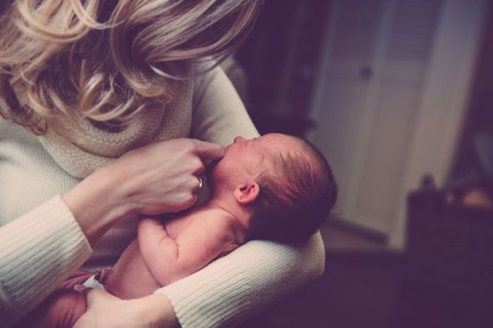 A mom holds a baby in her arms. 