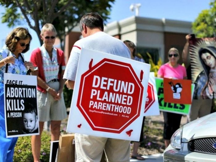 Pro-life activists pray before holding a protest rally against Planned Parenthood.