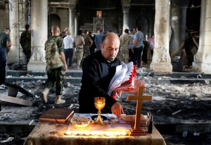 An Iraqi priest prepares for Sunday mass at the damaged Grand Immaculate Church in Qaraqosh, near Mosul, Iraq, on October 30, 2016.