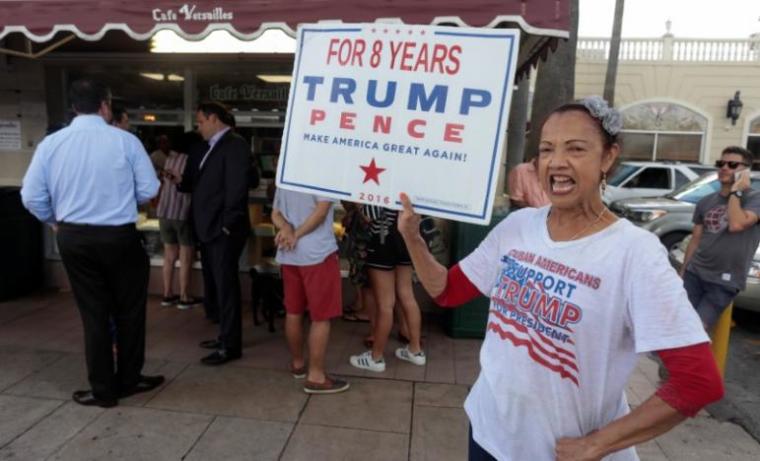 Madelyn del Rio, from Dominican Republic, holds a sign up in front of the Cuban popular Cafe Versailles in the Little Havana district as U.S. President Donald Trump is expected to announce changes to U.S.-Cuba policy, in Miami, Florida, U.S. June 16, 2017.