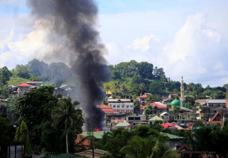 Smoke billowing from a burning building is seen as government troops continue their assault on insurgents from the Maute group, who have taken over large parts of Marawi City.