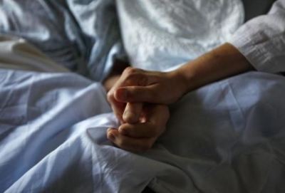 A photo of a woman holding the hand of her mother in the hospital.