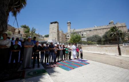 Palestinians attend the Friday prayer outside al-Ibrahimi mosque, which Jews call the Tomb of the Patriarchs, in the West Bank city of Hebron June 16, 2017.