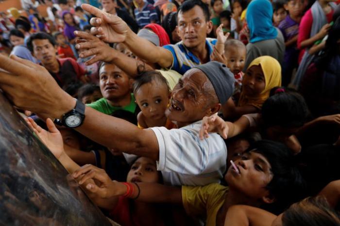 People reach to get ice cream at an evacuation center outside the city as army troops continue their assault against insurgents from the Maute group in Marawi city, Philippines, July 5, 2017.