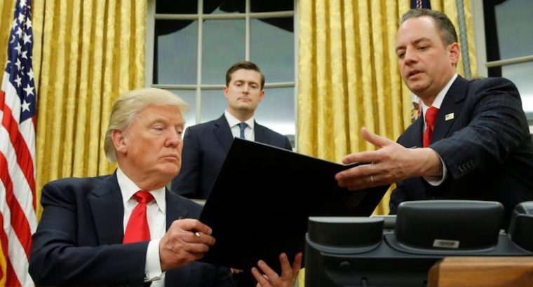 President Donald J. Trump, left, hands Chief of Staff Reince Priebus, right, an executive order in the Oval Office in Washington, D.C.