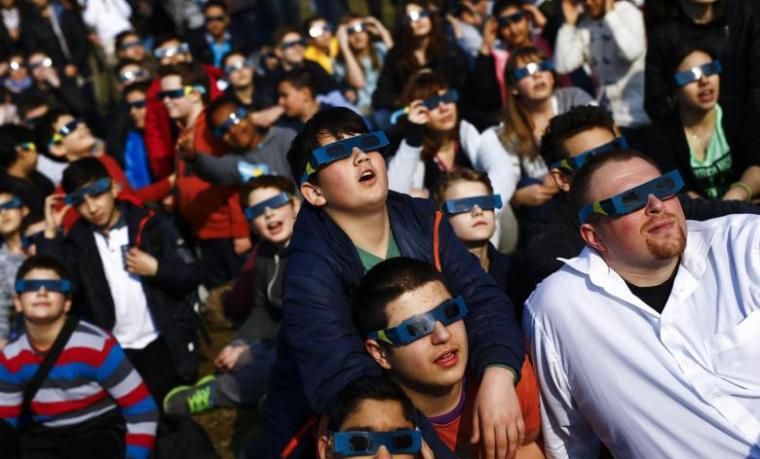 Pupils of the Deutschherren school and their teachers use protective glasses to watch a partial solar eclipse in Frankfurt, Germany, March 20, 2015.