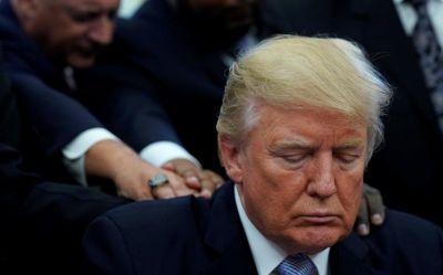 Faith leaders place their hands on the shoulders of U.S. President Donald Trump as he takes part in a prayer for those affected by Hurricane Harvey in the Oval Office of the White House in Washington, U.S., September 1, 2017.