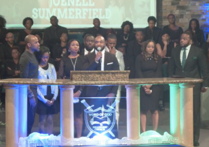 Joshua Summerfield (with mic), the youngest child of late pastors JoeNell and Frank Summerfield of Word of God Fellowship Church and Academy in Raleigh, North Carolina, talks about his parents at a memorial service for his mother on Monday, September 18, 2017. His siblings and other family members stand around him.