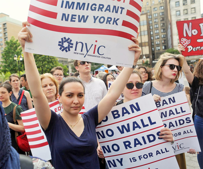 Protesters hold signs against U.S. President Donald Trump's limited travel ban in New York City.