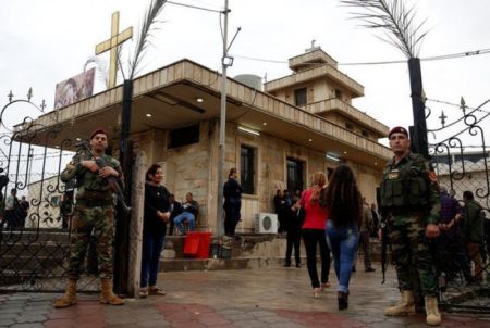 Kurdish security stand guard as Iraqi Orthodox Christians attend a prayer session inside Syriac Orthodox Church of Mart Shmoni during Good Friday prayers in Erbil, Iraq, April 14, 2017.