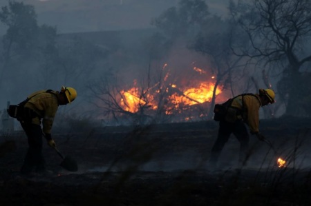 Firefighters work to put out hot spots on a fast moving wind driven wildfire in Orange, California, on Oct. 9, 2017.