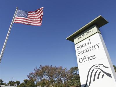 An American flag flutters in the wind next to signage for a United States Social Security Administration office in Burbank, California October 25, 2012.