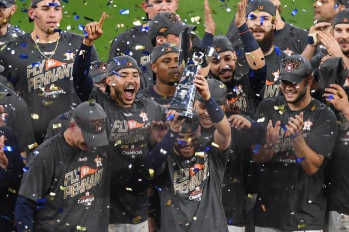 Houston Astros second baseman Jose Altuve (27) holds up the trophy after game seven of the 2017 ALCS playoff baseball series between the Houston Astros and the New York Yankees at Minute Maid Park, Houston, Texas, October 21, 2017.