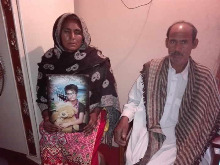 The Masih family holds up a picture of their son, Adnan, who was murdered in November 4, 2017.