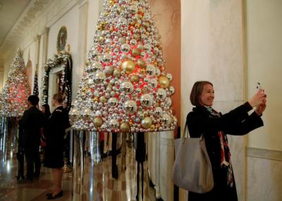 A woman takes a photo in the Cross Hall during a holiday decor preview of the White House in December 2016.