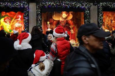 Credit : People wearing Christmas hats look in a shop window on Fifth Avenue during a busy shopping day in Manhattan, New York City, U.S. December 17, 2016.