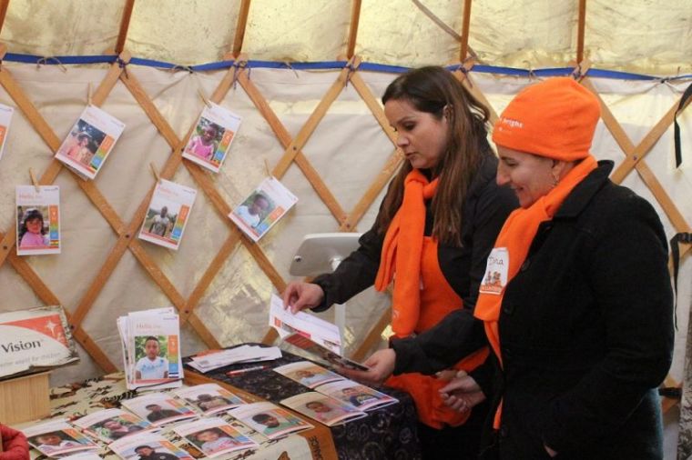 Wendy Pinero-DePencier, vice president of brand and communications at World Vision (background) discusses a child sponsor brochure with business owner and volunteer Dana Hadigian inside a Mongolian Ger at World Vision's interactive pop-up shop in New York City's Bryant Park on Tuesday November 28, 2017.