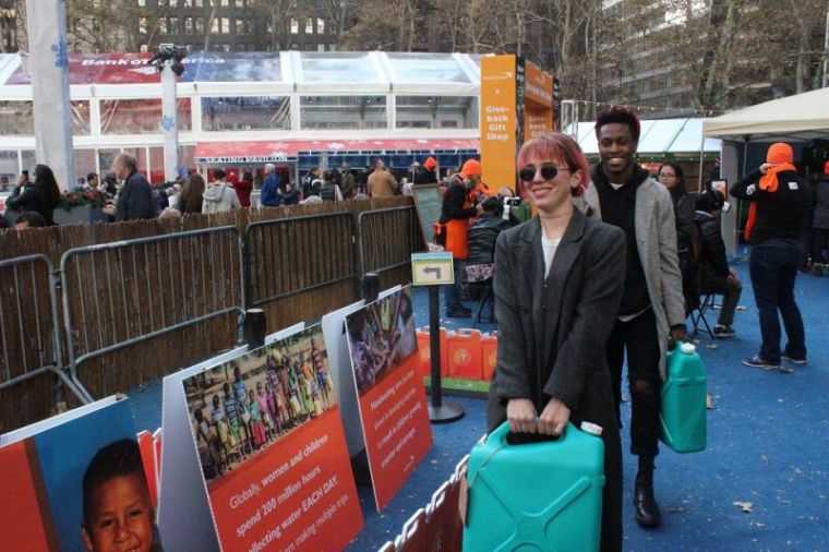 Jen Nista and Marlon Davis, both from Brooklyn do the water walk to experience what it's like for a child who walks hours a day to collect water at World Vision's interactive pop-up shop in New York City's Bryant Park on Tuesday November 28, 2017.