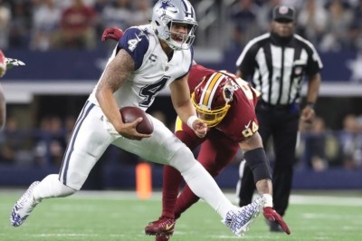 Dallas Cowboys quarterback Dak Prescott (4) runs the ball in the second quarter against Washington Redskins linebacker Preston Smith (94) at AT&T Stadium, Nov. 30, 2017.