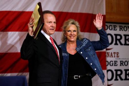 A supporter of Republican candidate for U.S. Senate Judge Roy Moore walks past an American flag before a campaign rally in Fairhope, Alabama, U.S., December 5, 2017.