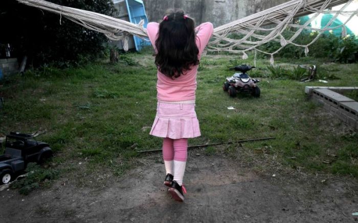 A biological boy who identifies as a girl named leans on a hammock at his home in Buenos Aires, Argentina.