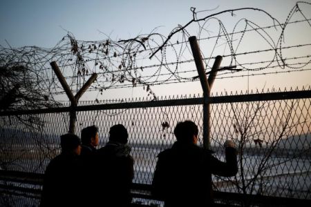 People look toward the north through a barbed-wire fence near the militarized zone separating the two Koreas, in Paju, South Korea, December 21, 2017.