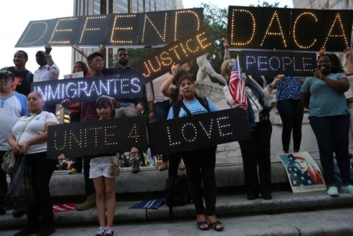 People hold signs against U.S. President Donald Trump's proposed end of the DACA program that protects immigrant children from deportation at a protest in New York City, U.S., August 30, 2017.