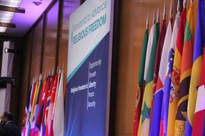 National flags flank a sign promoting the first-ever State Department Ministerial to Advance Religious Freedom at the Harry S. Truman Building in Washington, D.C. on July 24, 2018.