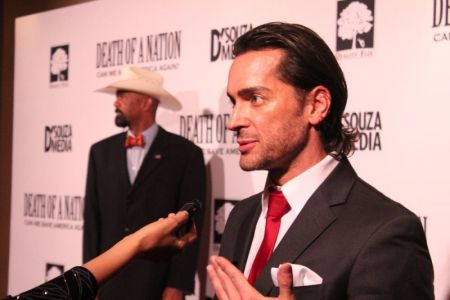 Brandon Straka speaks to reporters at the advanced screening of Dinesh D'Souza's documentary 'Death of a Nation' at the E Street Cinema in Washington, D.C. on Aug. 1, 2018 while former Milwaukee County Sheriff David Clarke posed for the cameras in the background.