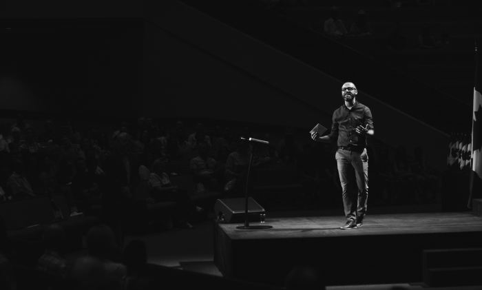 Pastor on stage holding Bible.