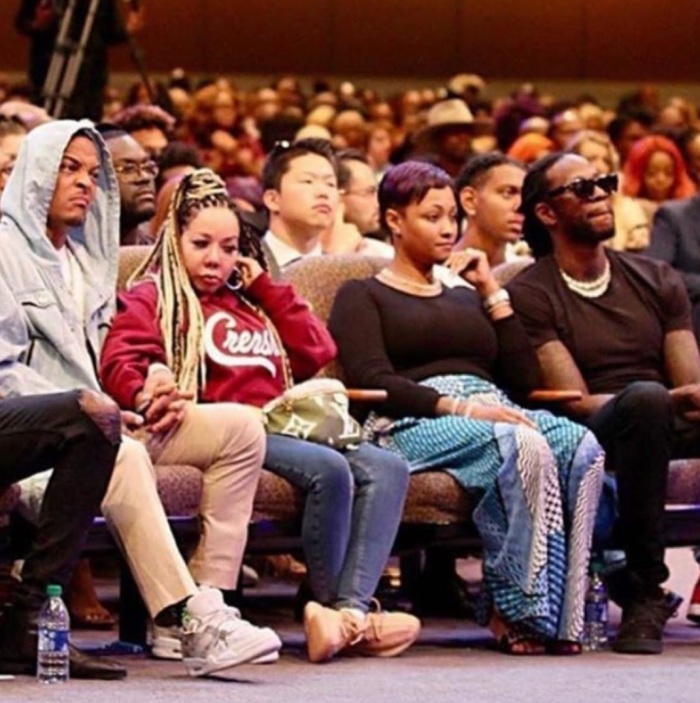 Rapper T.I. (L) smirks next to his wife as he listens to Bishop I.V. Hilliard ask congregants for money at New Birth Missionary Baptist Church in Stonecrest, Ga.